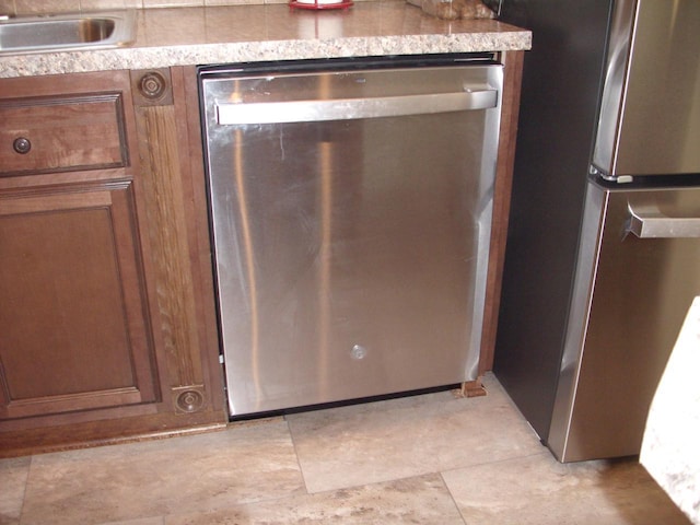 interior details with a sink, stainless steel appliances, and brown cabinetry