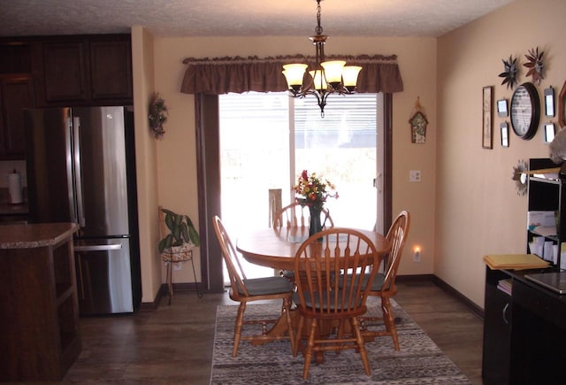 dining area with a textured ceiling, baseboards, dark wood-type flooring, and an inviting chandelier