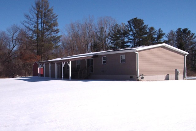 snow covered back of property featuring crawl space