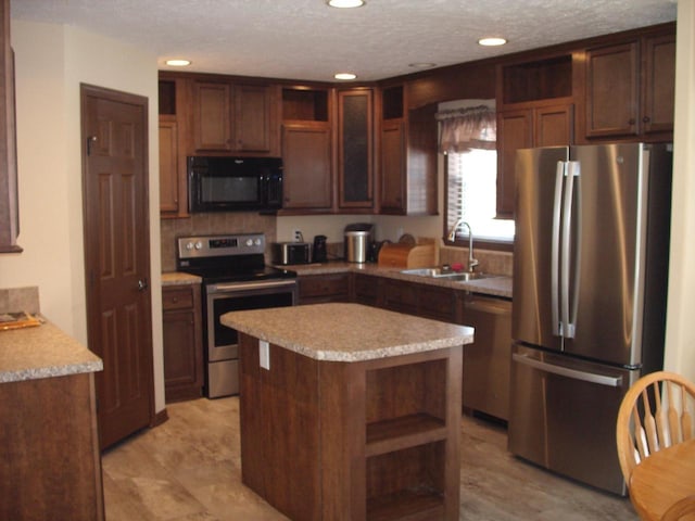 kitchen with open shelves, appliances with stainless steel finishes, light countertops, and a sink