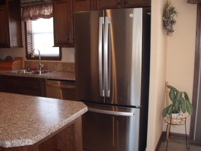 kitchen featuring appliances with stainless steel finishes, light countertops, baseboards, and a sink