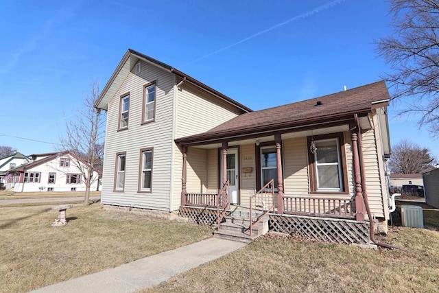 traditional-style home with central AC unit, covered porch, and a front yard