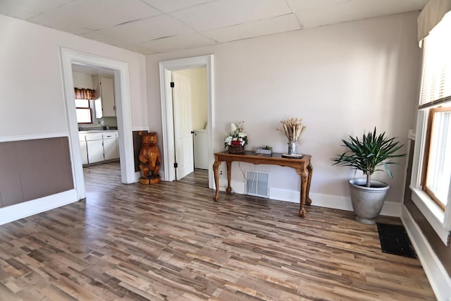 interior space with visible vents, a paneled ceiling, baseboards, and wood finished floors