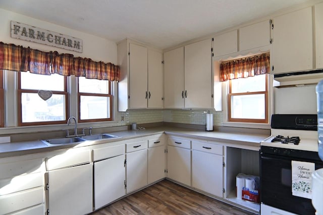 kitchen with a sink, under cabinet range hood, range with gas stovetop, light countertops, and decorative backsplash