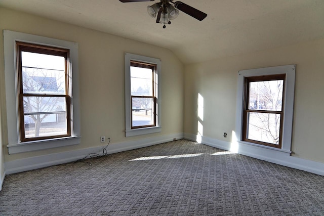 carpeted empty room featuring baseboards, ceiling fan, and vaulted ceiling