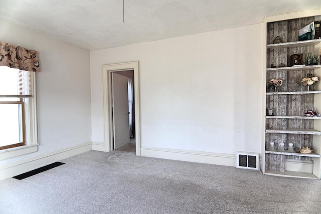 carpeted empty room with baseboards and visible vents