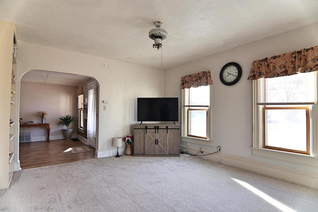 unfurnished living room with baseboards, arched walkways, and carpet flooring