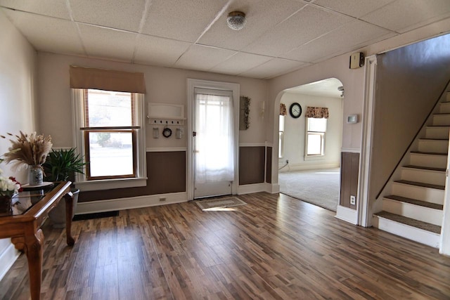 foyer entrance with a paneled ceiling, arched walkways, wood finished floors, and stairs