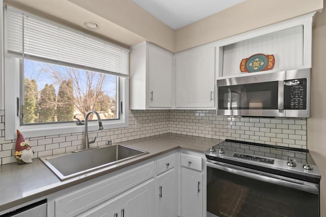 kitchen featuring tasteful backsplash, appliances with stainless steel finishes, white cabinetry, and a sink