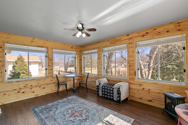 sunroom / solarium with a wealth of natural light, ceiling fan, and a wood stove