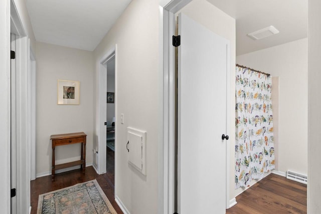 corridor with a baseboard heating unit, baseboards, and wood finished floors