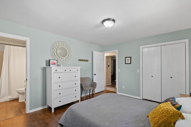 bedroom with ensuite bathroom, dark wood-style floors, baseboards, and a closet