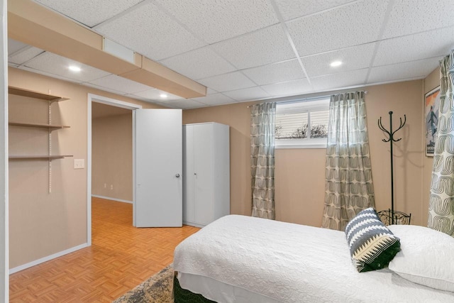 bedroom featuring a closet, recessed lighting, a paneled ceiling, and baseboards