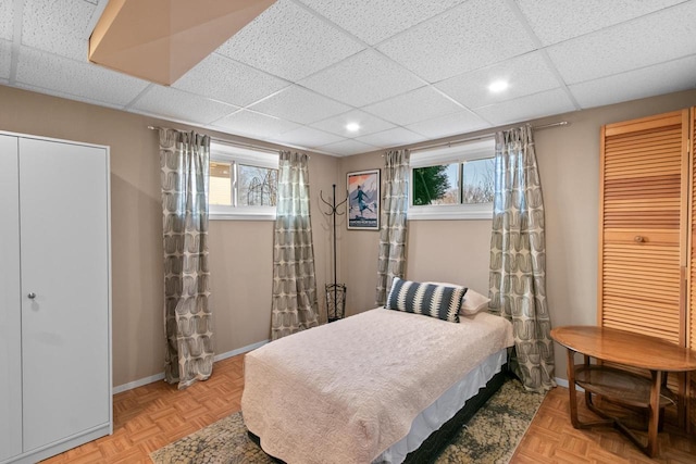 bedroom featuring a paneled ceiling and baseboards