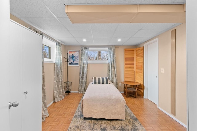 bedroom with recessed lighting, a paneled ceiling, and baseboards