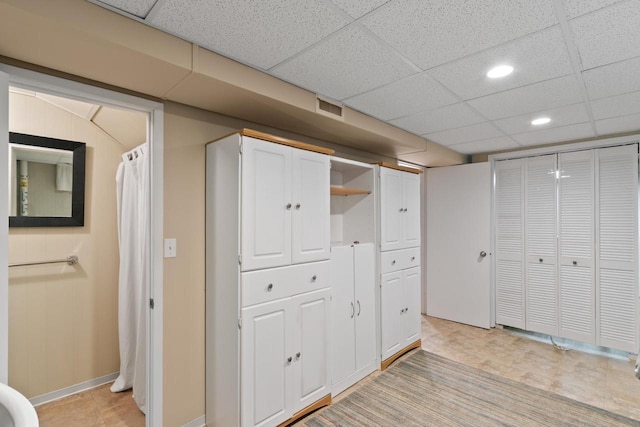 finished below grade area featuring visible vents, recessed lighting, a paneled ceiling, and baseboards