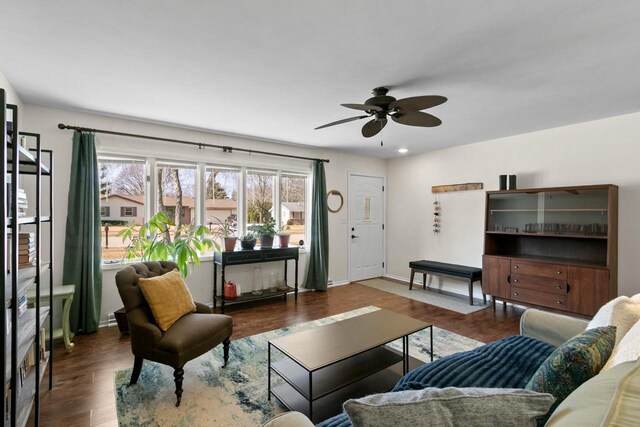 living room featuring baseboards, ceiling fan, and wood finished floors