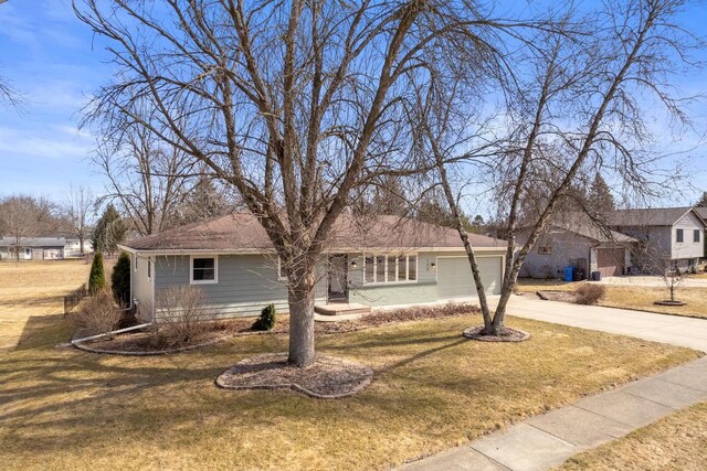 single story home with concrete driveway, an attached garage, and a front yard