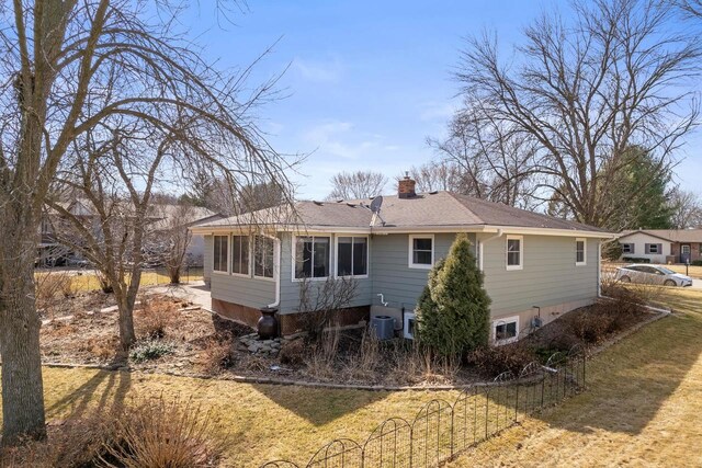 rear view of property with a shingled roof, fence, central AC unit, a lawn, and a chimney