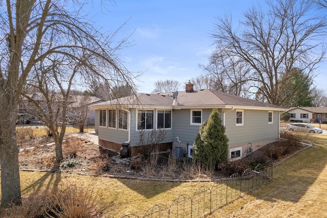 back of property featuring a shingled roof, fence, a lawn, and a chimney