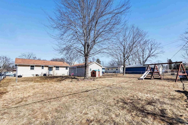 view of yard featuring a playground, an outdoor structure, and fence