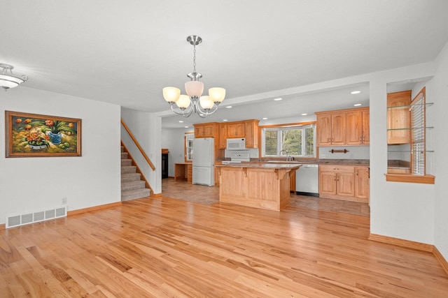 kitchen featuring visible vents, a breakfast bar, a kitchen island, white appliances, and light wood finished floors