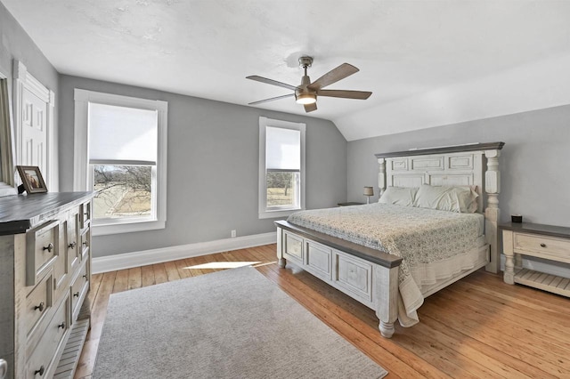 bedroom featuring ceiling fan, baseboards, lofted ceiling, and light wood-style floors