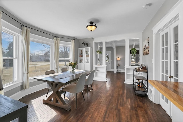 dining area with decorative columns, wood-type flooring, and baseboards