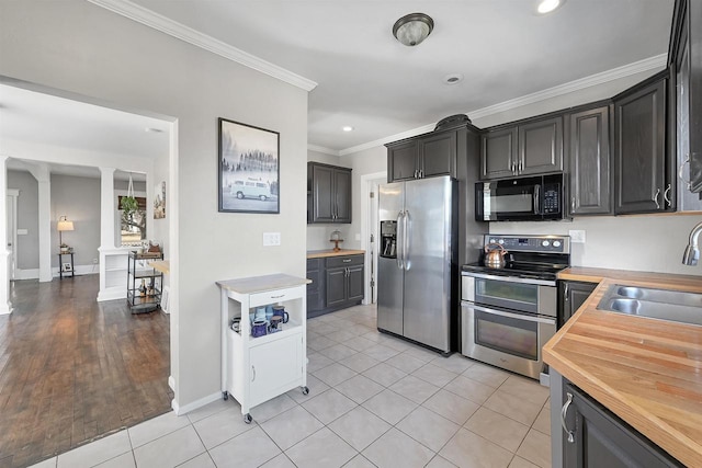 kitchen with butcher block countertops, ornamental molding, a sink, stainless steel appliances, and decorative columns