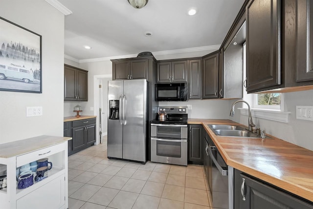 kitchen with wooden counters, light tile patterned flooring, a sink, stainless steel appliances, and crown molding