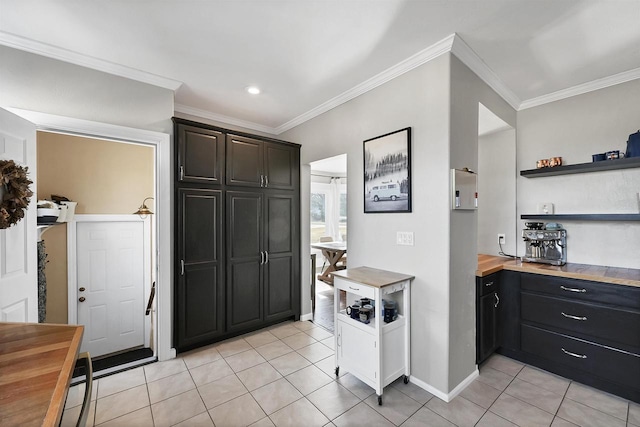 kitchen with baseboards, butcher block counters, ornamental molding, light tile patterned floors, and open shelves