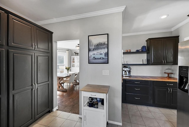 kitchen featuring butcher block countertops, open shelves, stainless steel fridge, light tile patterned flooring, and crown molding