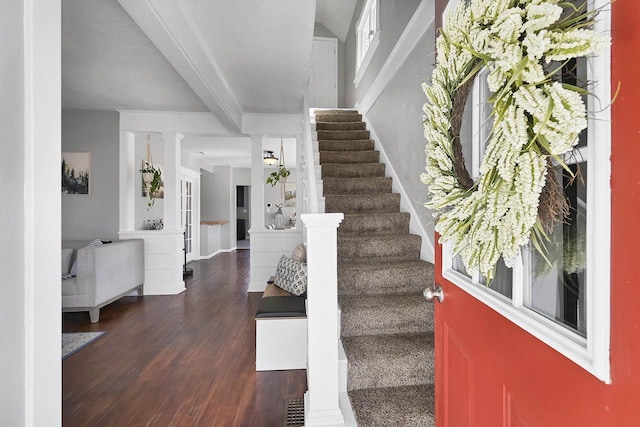 foyer entrance with decorative columns, beam ceiling, wood finished floors, and stairs