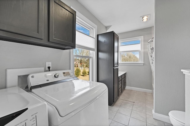 laundry room with washer and dryer, laundry area, light tile patterned flooring, and baseboards