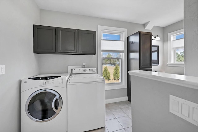 laundry room featuring washing machine and clothes dryer, cabinet space, baseboards, and light tile patterned flooring