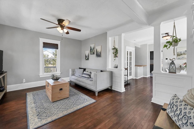 living area with beam ceiling, dark wood-type flooring, a ceiling fan, decorative columns, and baseboards