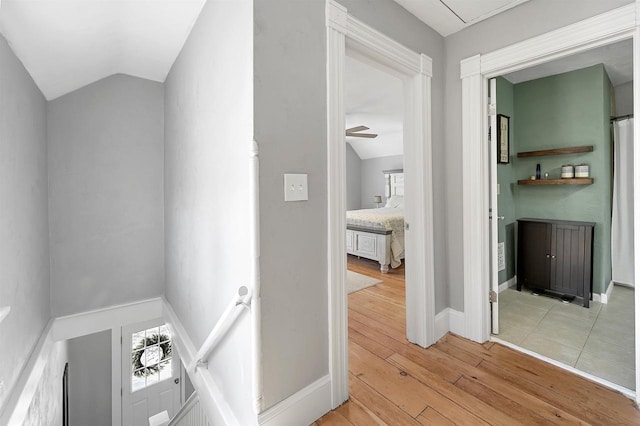 hall with vaulted ceiling, a wealth of natural light, baseboards, and light wood finished floors