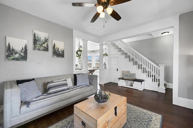 living area featuring baseboards, stairs, decorative columns, wood finished floors, and a ceiling fan