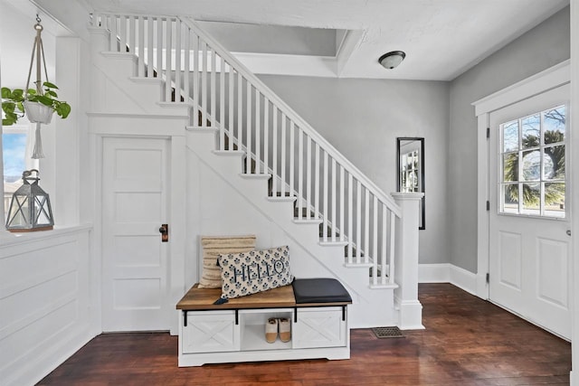 foyer featuring baseboards, wood finished floors, and stairs