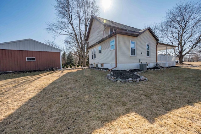 view of side of property with cooling unit and a lawn