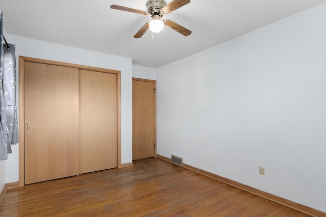 unfurnished bedroom with visible vents, wood finished floors, a closet, baseboards, and ceiling fan