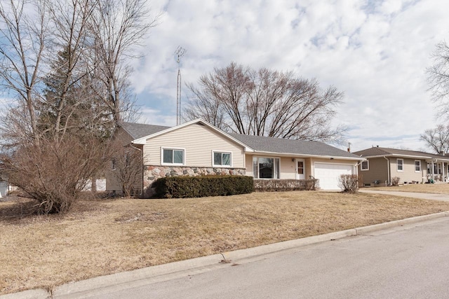 ranch-style house with driveway, stone siding, a front yard, and an attached garage