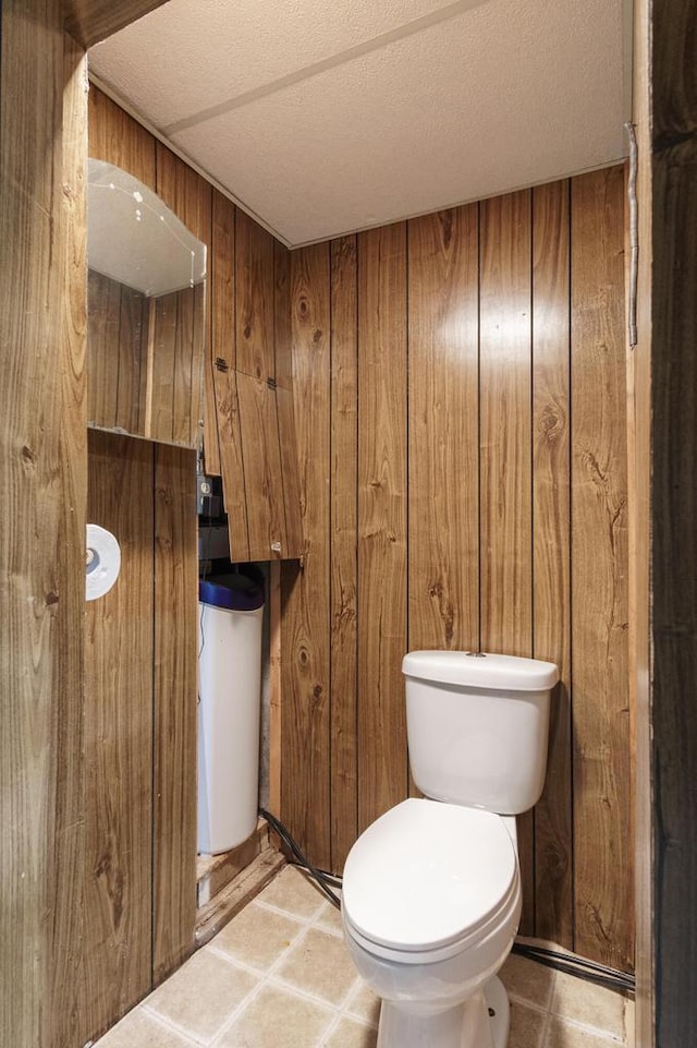 half bath featuring toilet, wood walls, and a textured ceiling