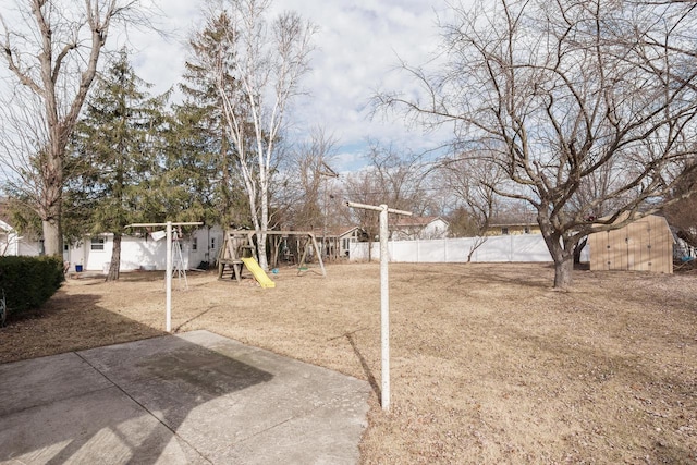 view of yard with an outbuilding, fence, playground community, and a shed