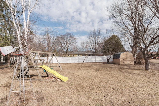 view of yard featuring a shed, a playground, an outdoor structure, and fence