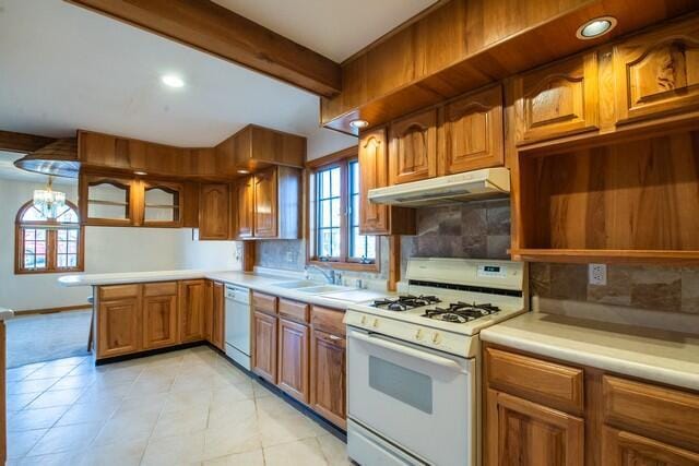 kitchen featuring white appliances, beam ceiling, a sink, under cabinet range hood, and brown cabinets