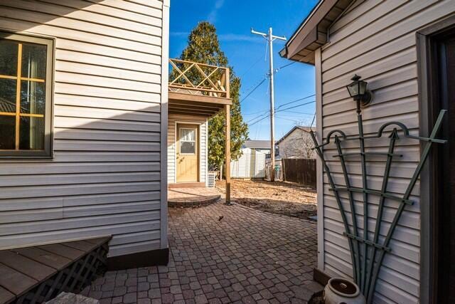 view of side of property with a patio, an outdoor structure, and fence