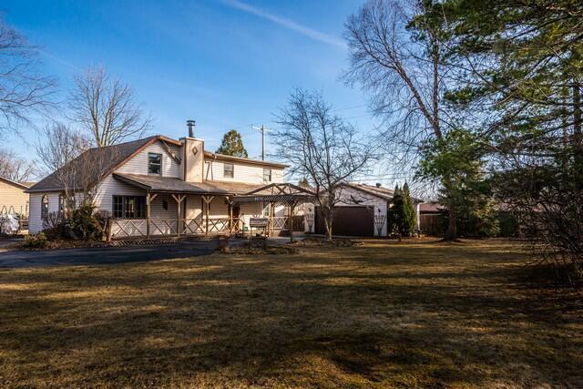 back of house featuring a gazebo, a lawn, and a chimney