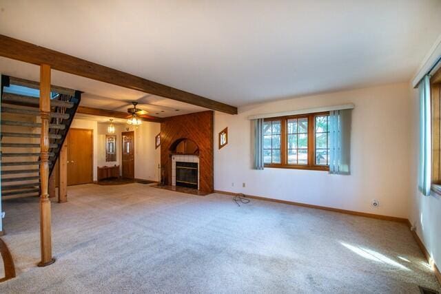 unfurnished living room featuring stairs, beamed ceiling, a fireplace, and baseboards