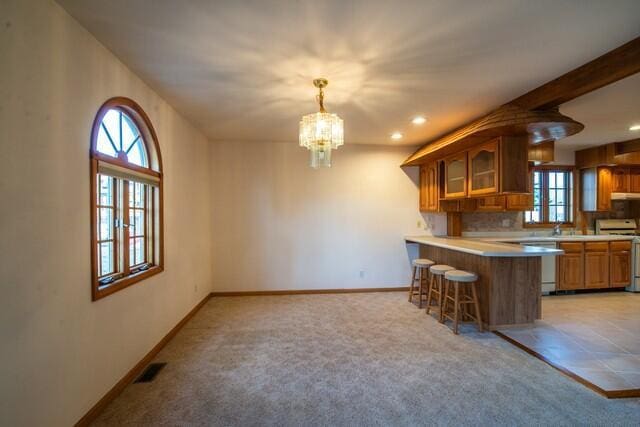 kitchen with light colored carpet, a breakfast bar area, electric stove, and baseboards